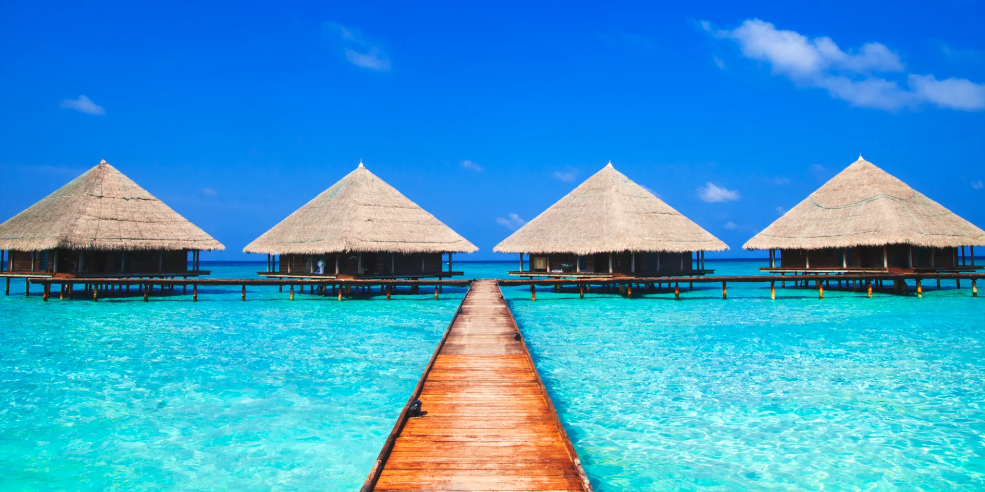 Overwater bungalow huts over turquoise lagoon